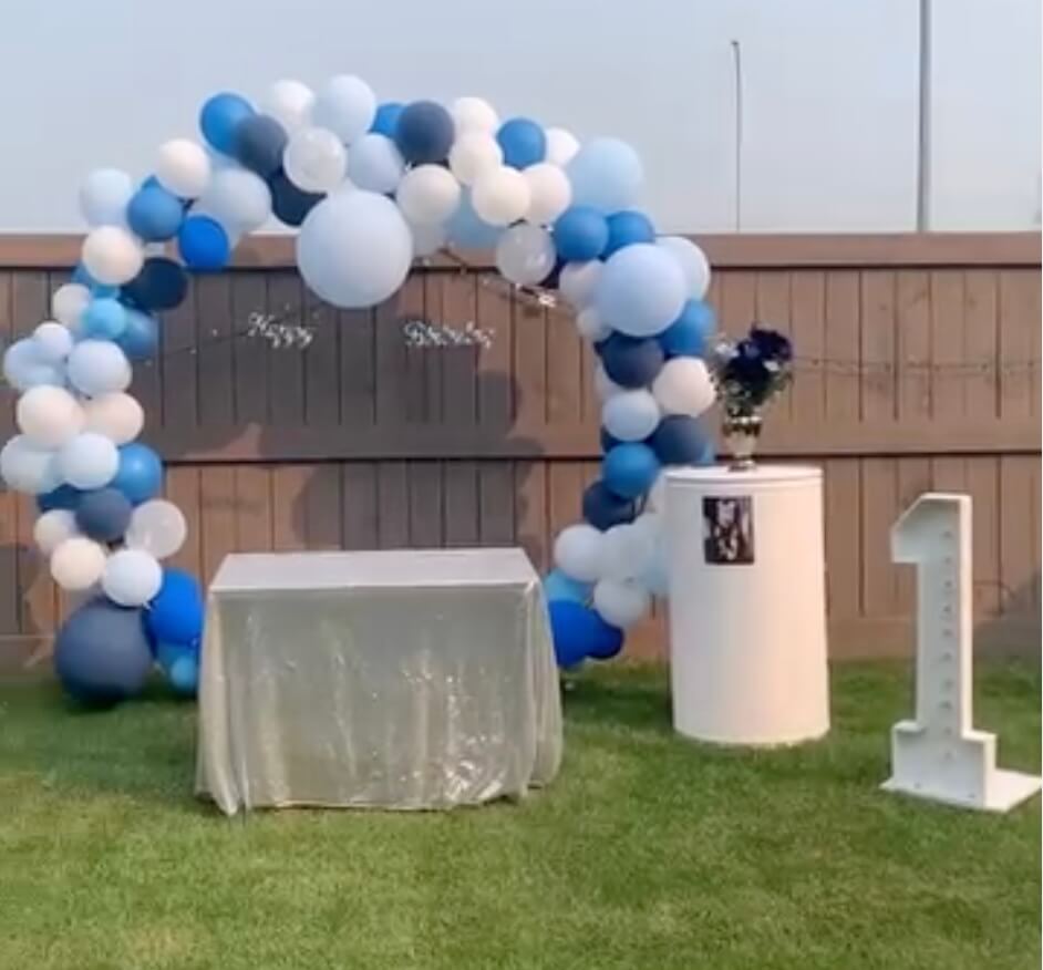 Graduation party setup with large balloon arch and gold-themed decor