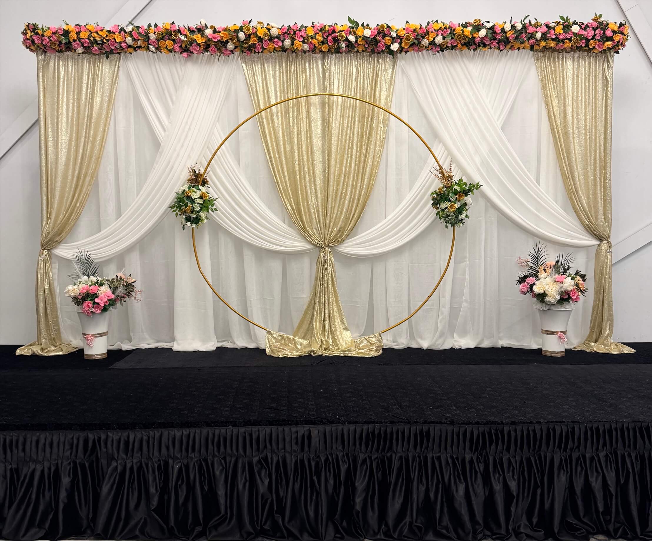 Luxurious red and gold wedding stage decor with draped fabrics and floral arches in Edmonton